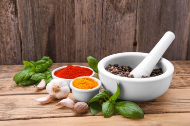 Photo of Mortar with pestle and different spices on wooden table