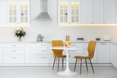 Photo of Table with orange chairs in modern kitchen interior