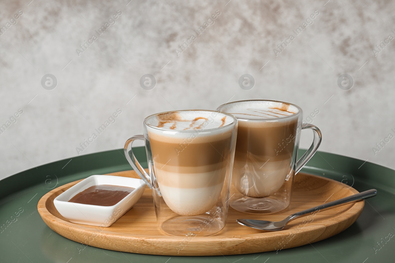 Photo of Tray with caramel macchiato in glass cups and syrup on table