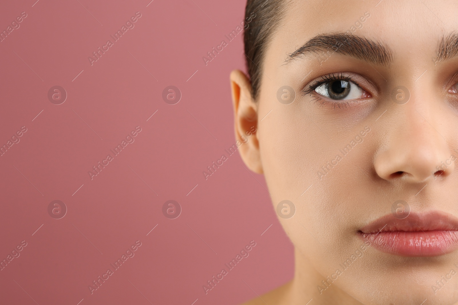 Photo of Young woman with perfect eyebrows on pink background, closeup. Space for text