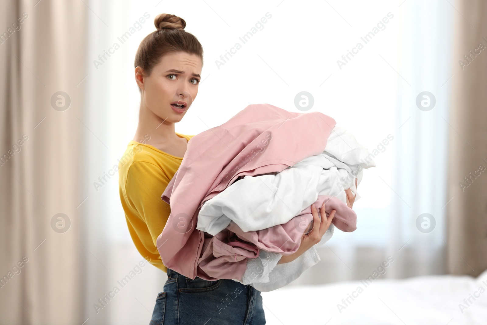 Photo of Woman holding pile of dirty laundry indoors