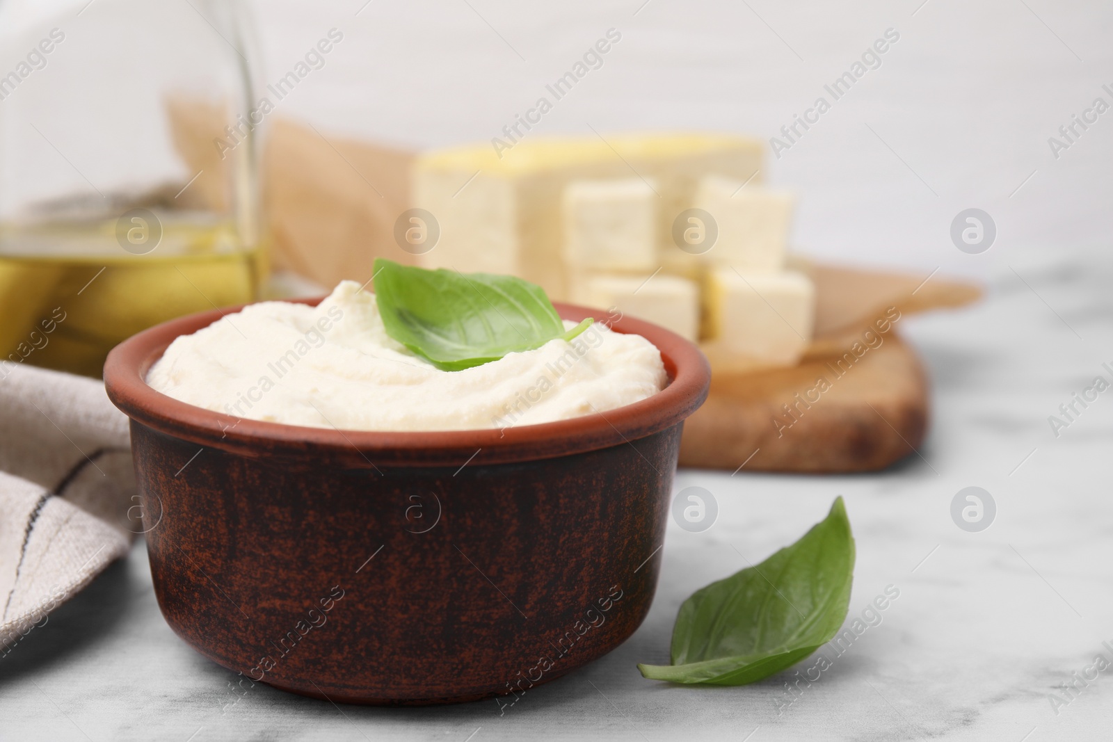 Photo of Delicious tofu sauce and basil leaves on white marble table, closeup. Space for text