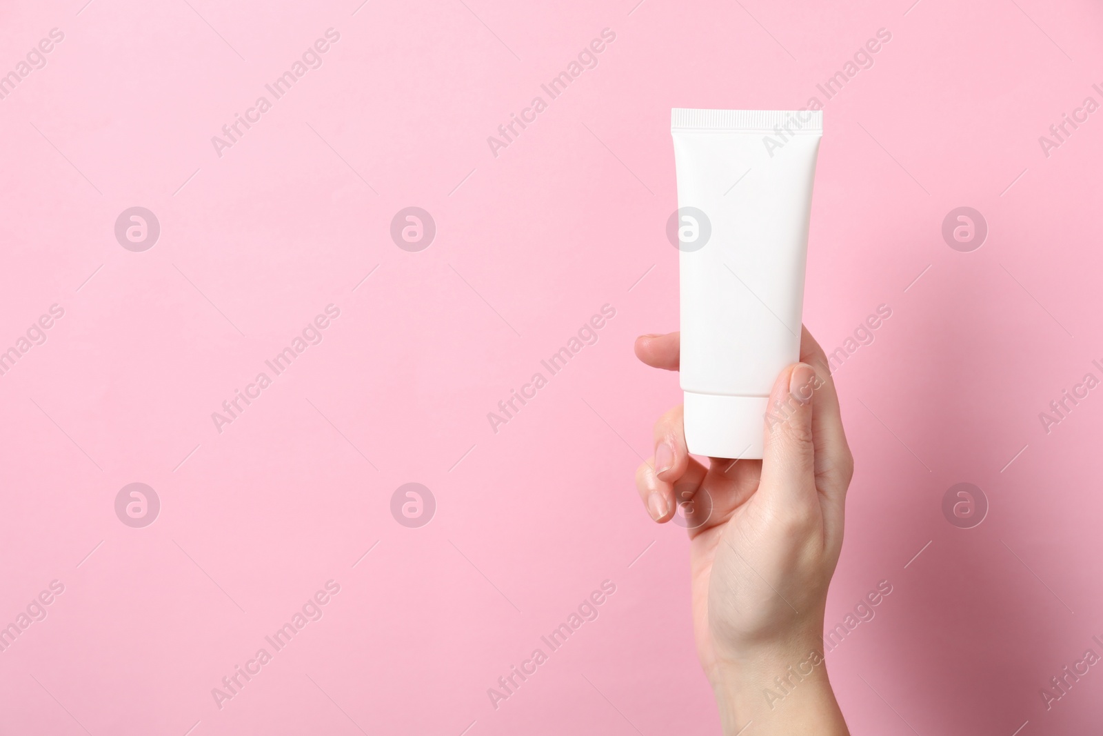 Photo of Woman with tube of hand cream on pink background, closeup. Space for text