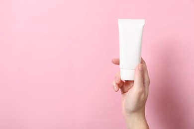 Photo of Woman with tube of hand cream on pink background, closeup. Space for text