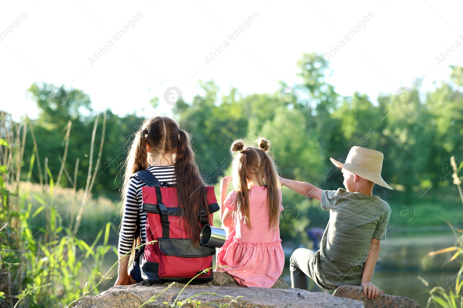 Photo of Little children sitting on rock outdoors. Summer camp