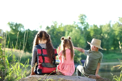 Little children sitting on rock outdoors. Summer camp