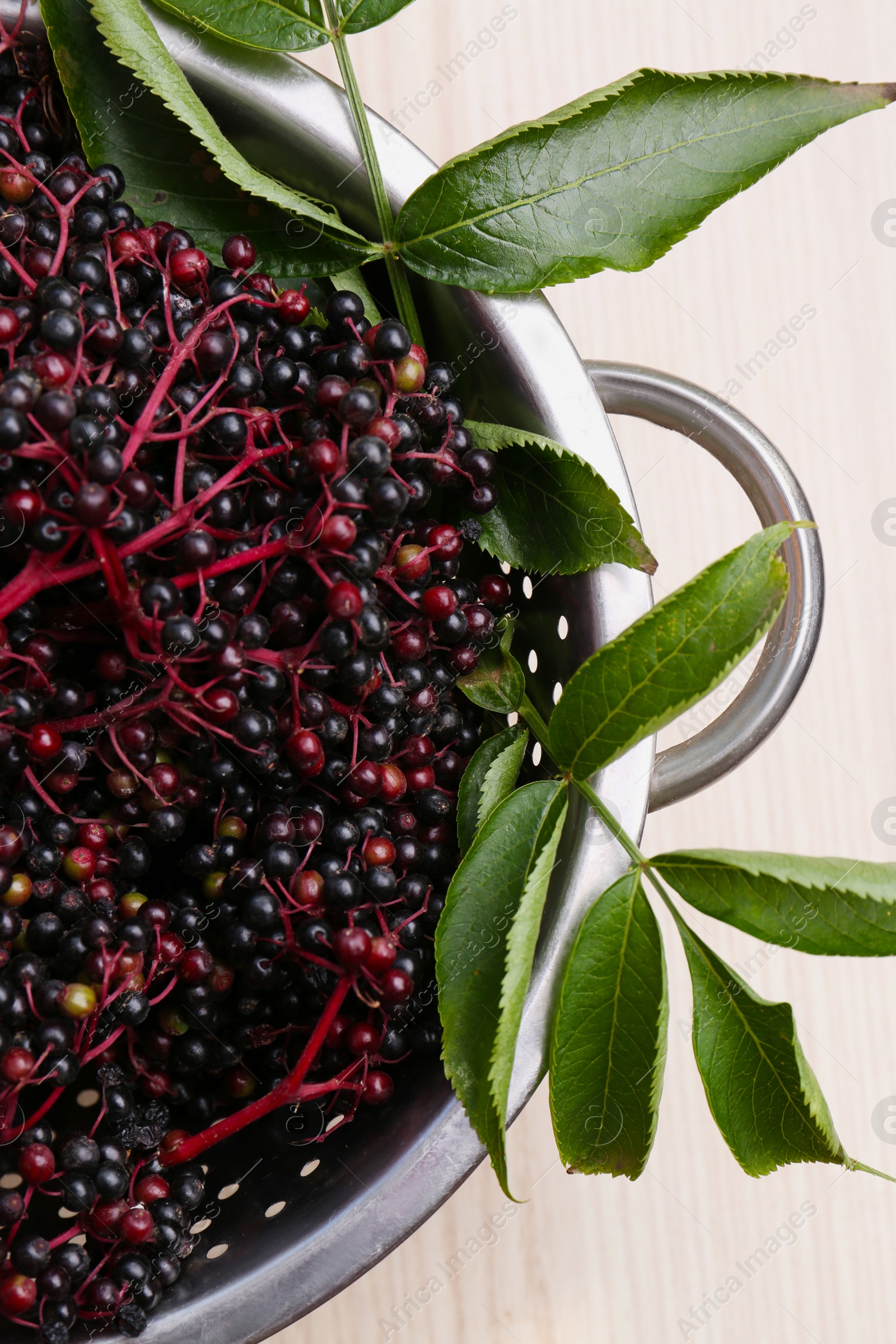 Photo of Tasty elderberries (Sambucus) on wooden table, top view