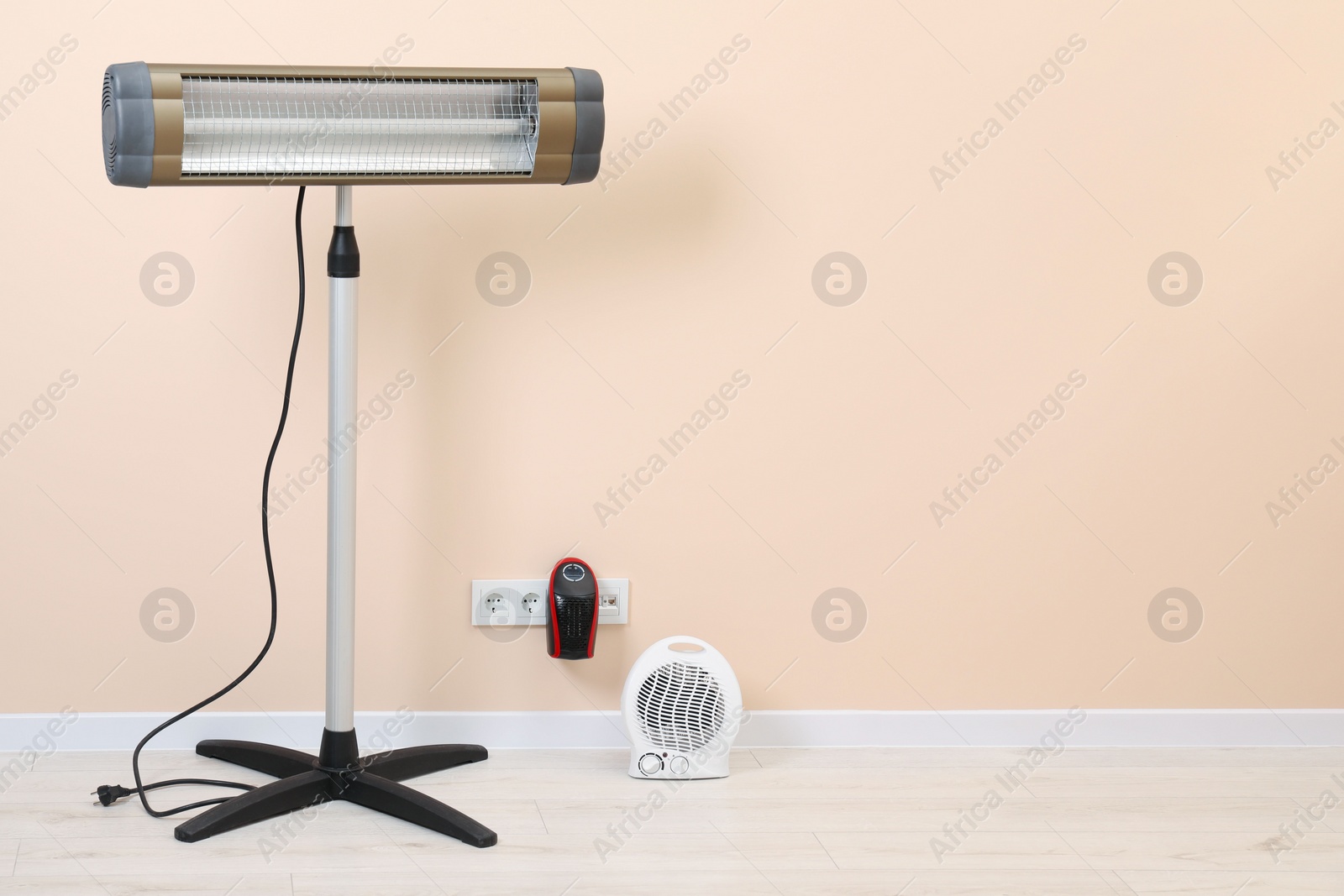 Photo of Different electric heaters near beige wall indoors, space for text