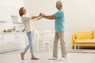Photo of Happy senior couple dancing in kitchen at home