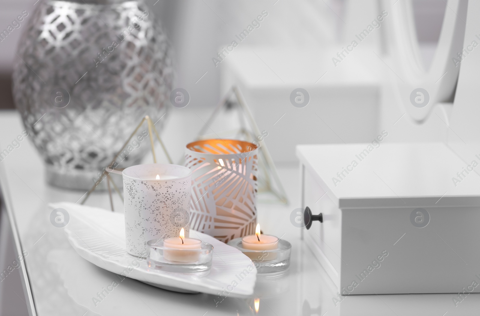 Photo of Burning candles in beautiful holders on table indoors