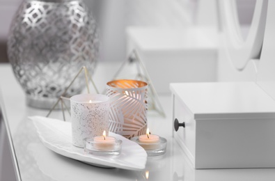 Burning candles in beautiful holders on table indoors