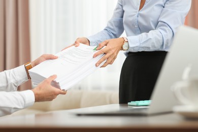 Woman giving documents to colleague in office, closeup