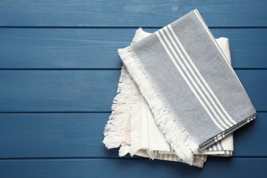 Photo of Striped kitchen towels on blue wooden table, top view. Space for text