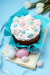 Traditional Easter cake with meringues and painted eggs on light blue background