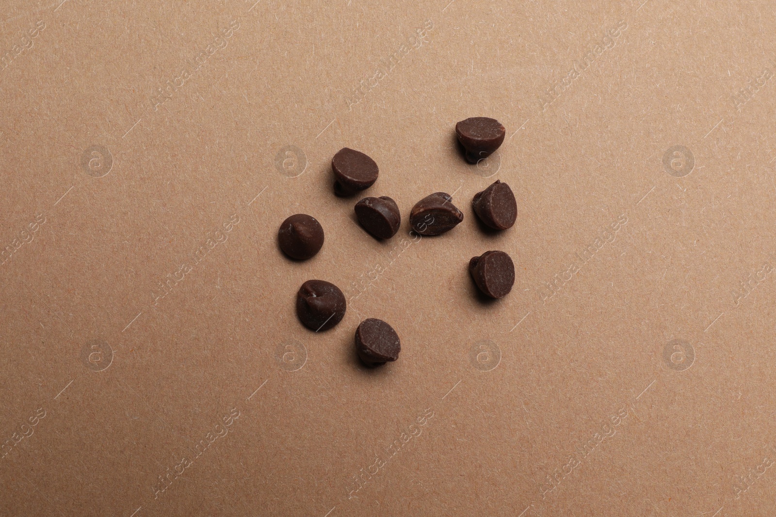 Photo of Delicious chocolate chips on brown background, top view