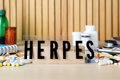 Word Herpes and different pills on wooden table