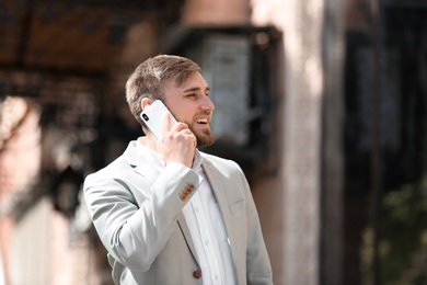 Portrait of young businessman talking on phone outdoors