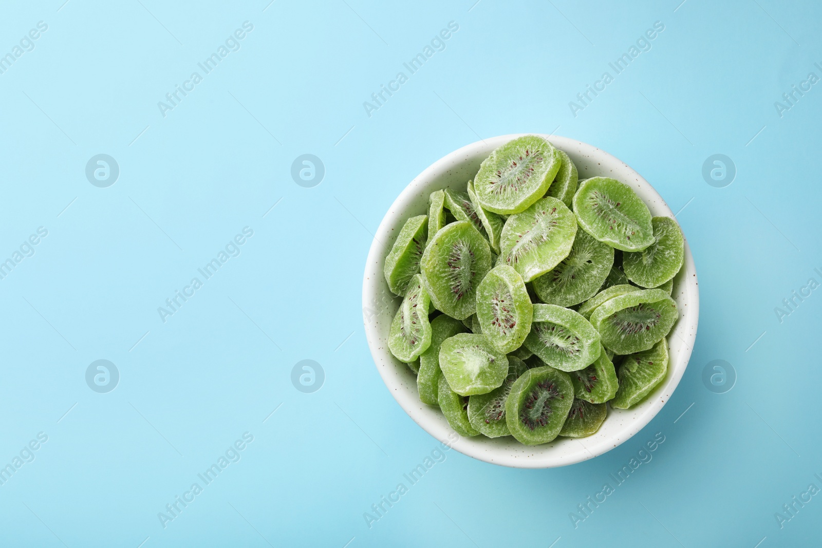 Photo of Bowl of dried kiwi on color background, top view with space for text. Tasty and healthy fruit