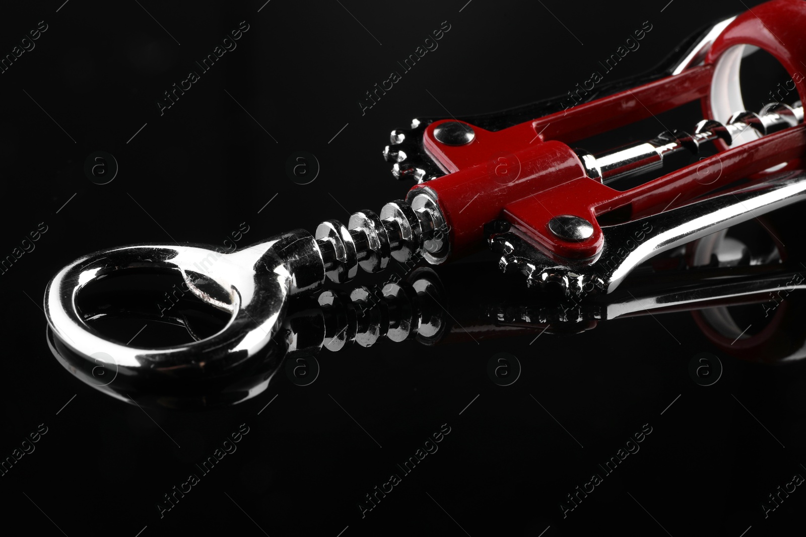 Photo of One wing corkscrew on dark mirror table, closeup