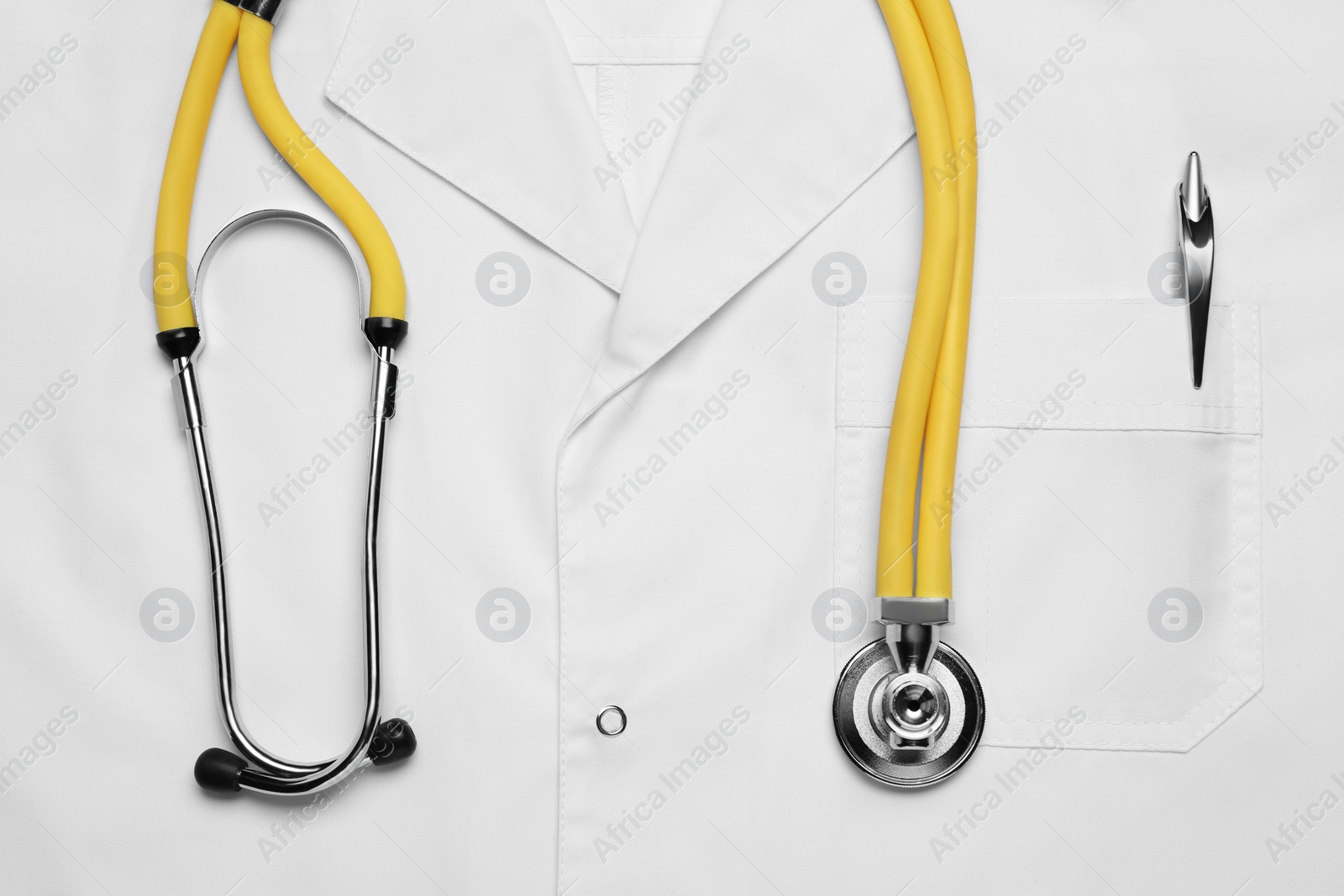 Photo of Stethoscope on white medical uniform, top view