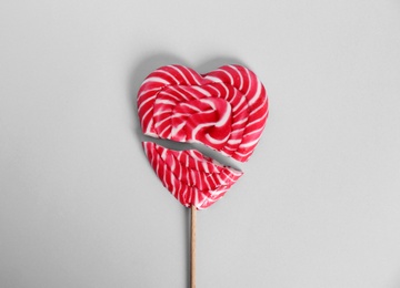 Photo of Broken heart shaped lollipop on white background, top view