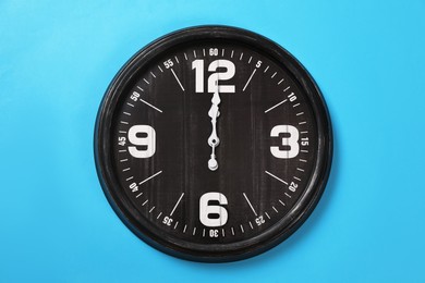 Photo of Stylish analog clock hanging on light blue wall