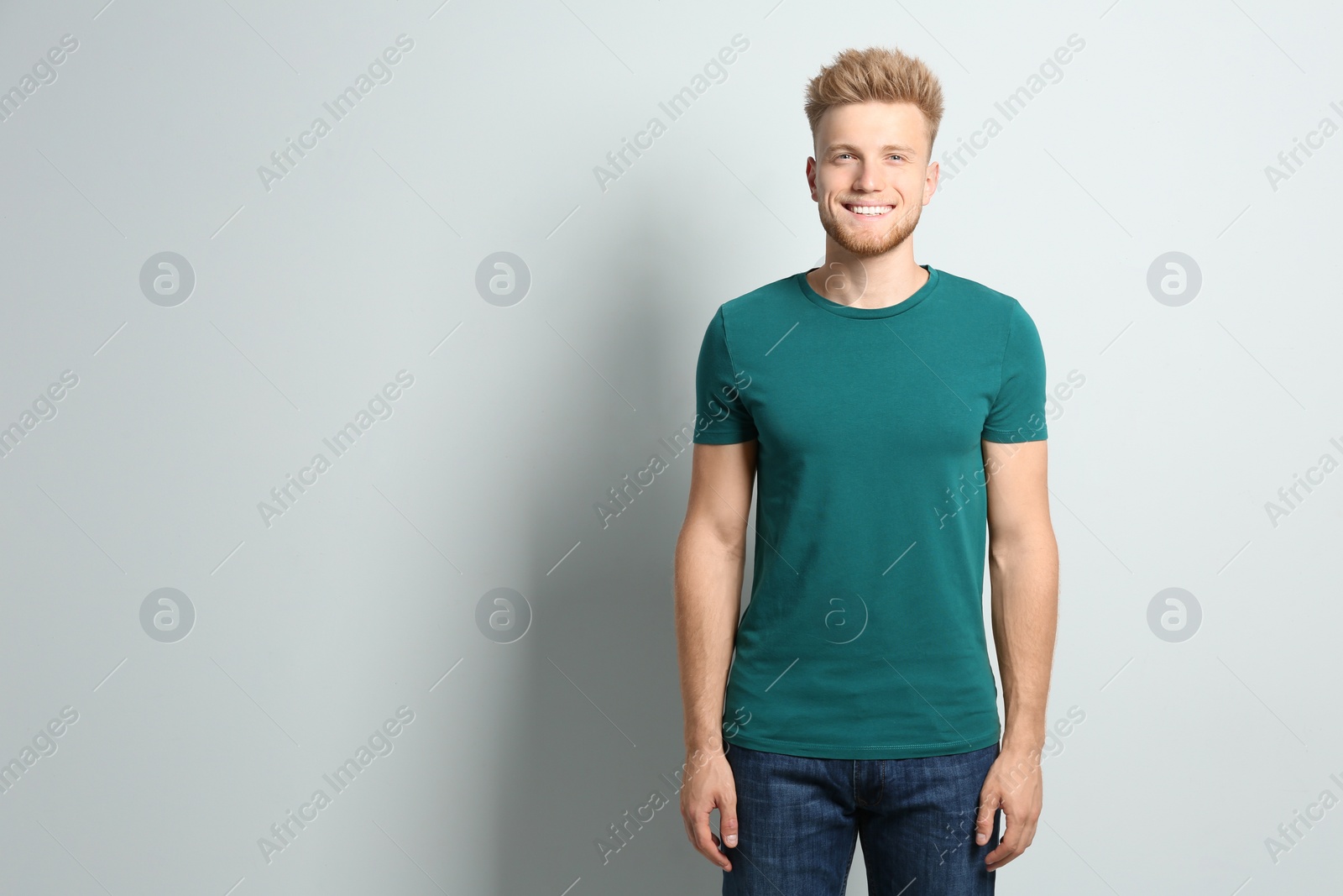 Photo of Young man wearing blank t-shirt on light background. Mockup for design