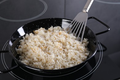 Photo of Cooking tasty rice on induction stove in kitchen, closeup