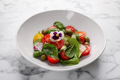 Photo of Delicious salad with vegetables and olives on white marble table