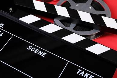 Clapperboard and film reel on red background, closeup