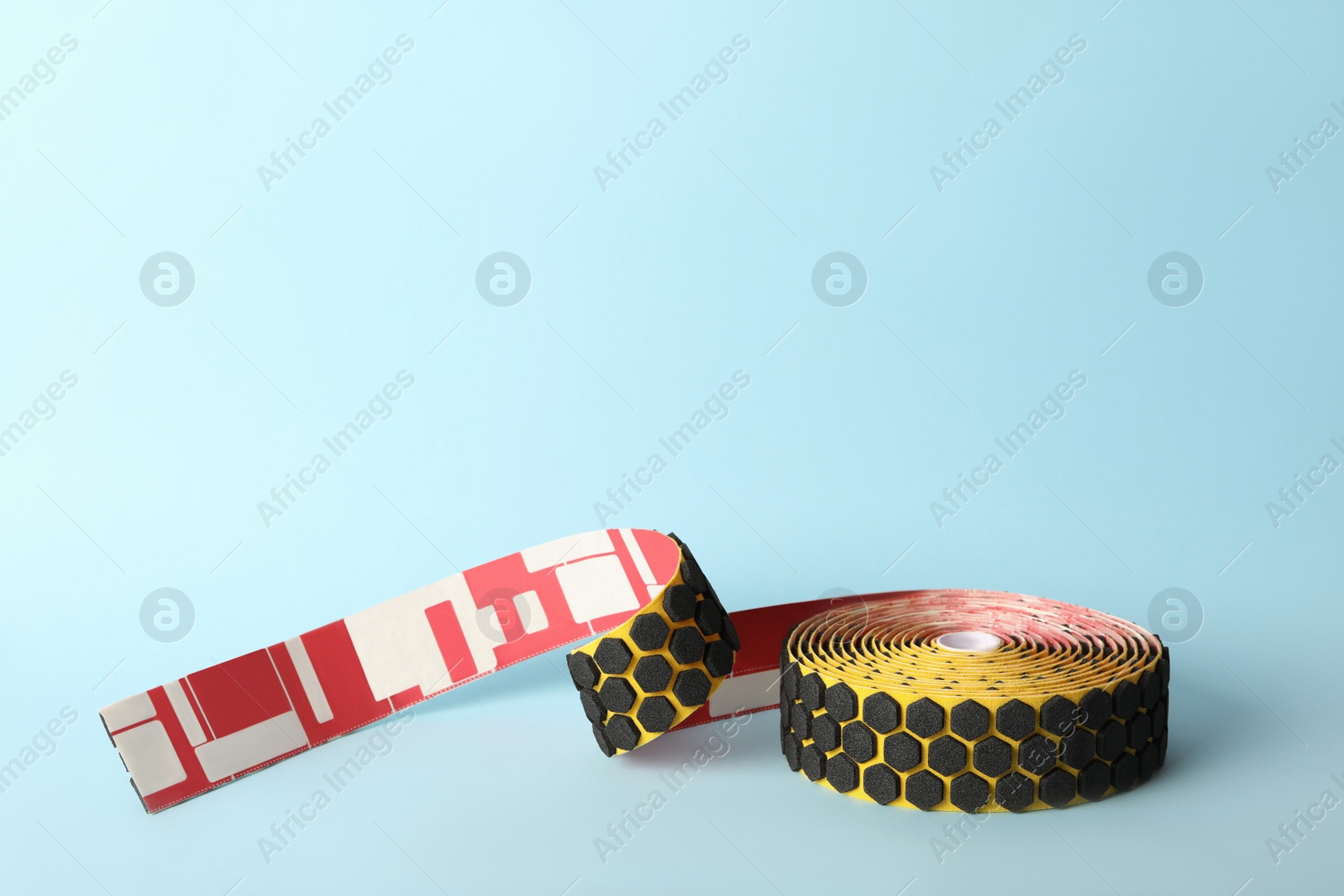 Photo of Bright kinesio tape in roll on light blue background. Space for text