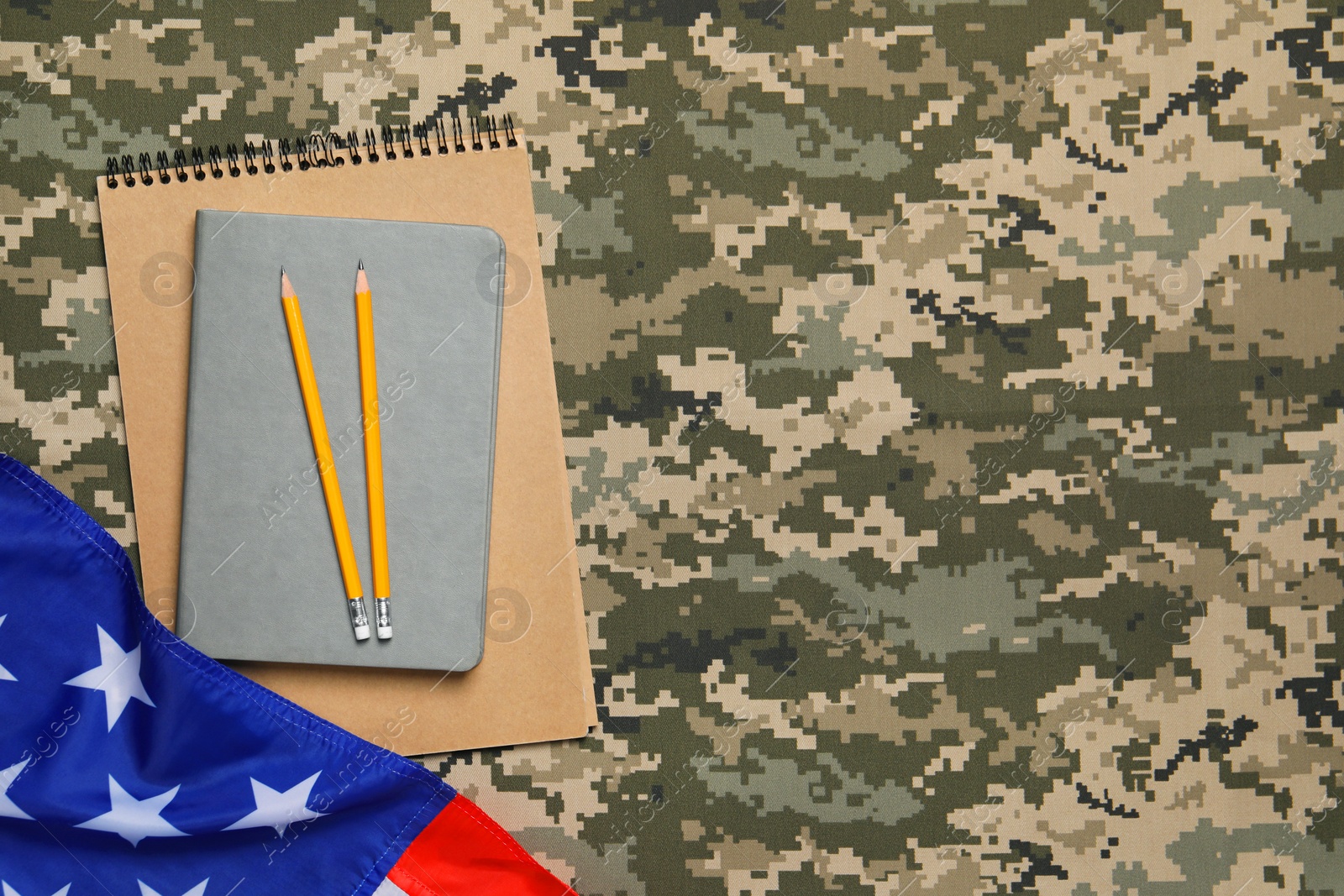 Photo of Notebooks, pencils and flag of United States on camouflage background, flat lay with space for text. Military education