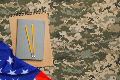 Photo of Notebooks, pencils and flag of United States on camouflage background, flat lay with space for text. Military education