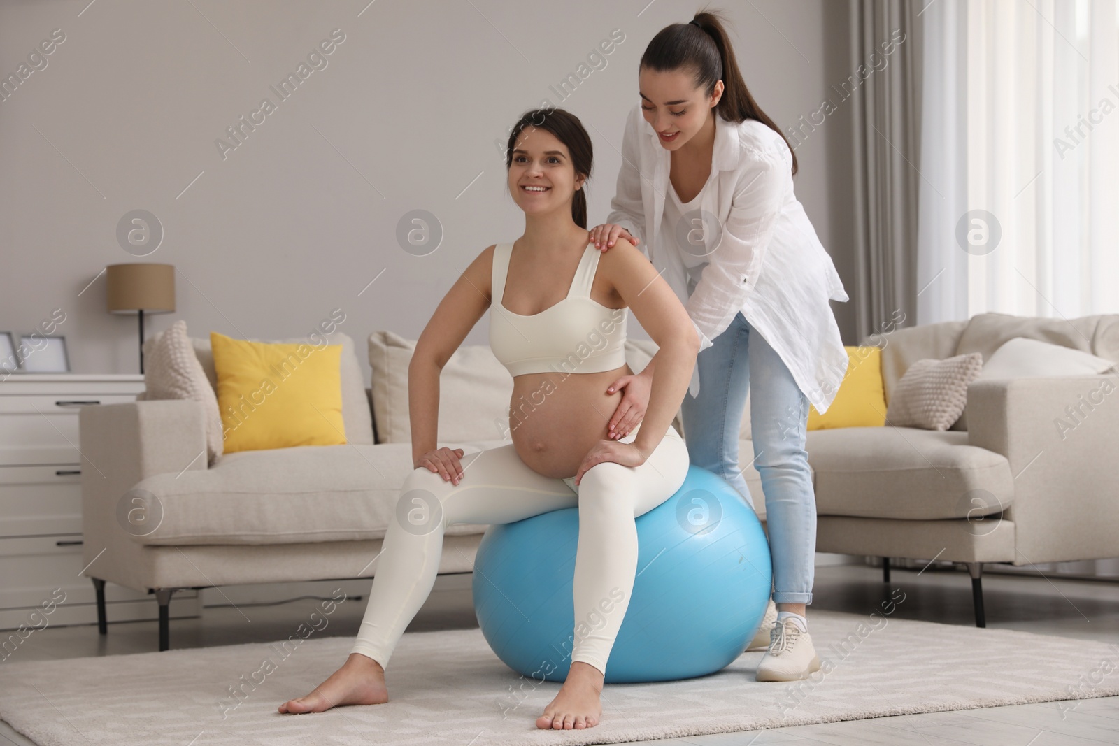 Photo of Doula working with pregnant woman in living room. Preparation for child birth