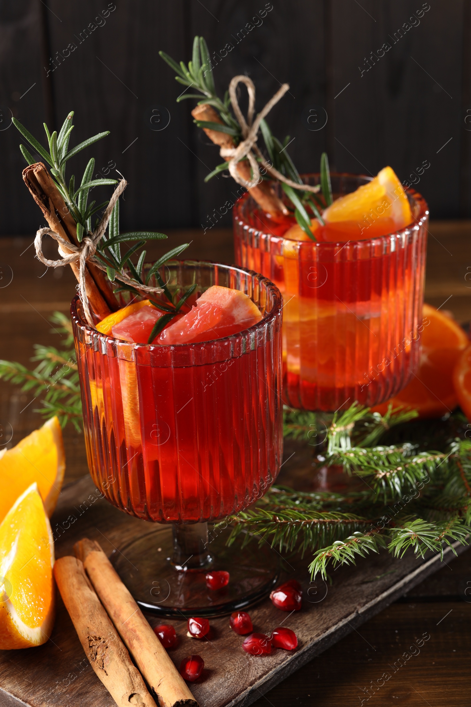 Photo of Christmas Sangria cocktail in glasses, ingredients and fir tree branches on wooden table, closeup