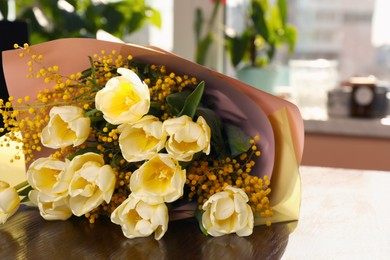 Photo of Bouquet with beautiful tulips and mimosa flowers on wooden table indoors