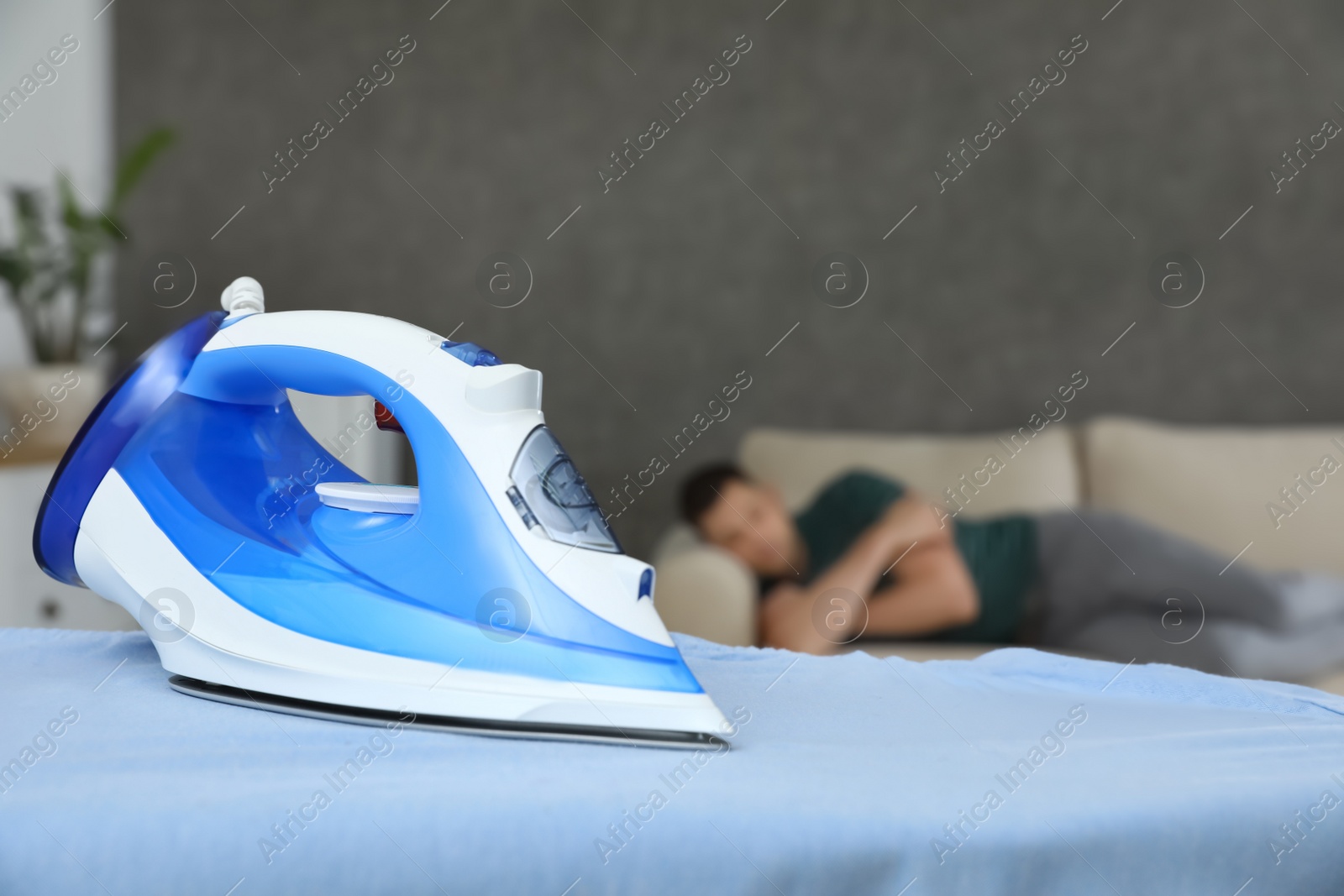 Photo of Modern iron and sleeping man in room. Space for text