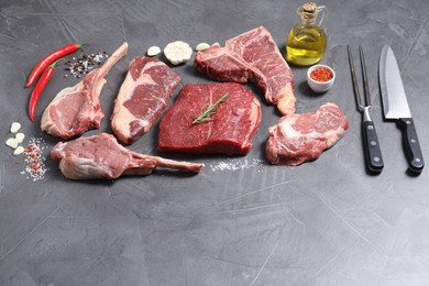 Photo of Fresh raw beef cuts, spices and butcher tools on light grey textured table, above view. Space for text