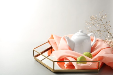 Photo of Tray with teapot and macarons on light background