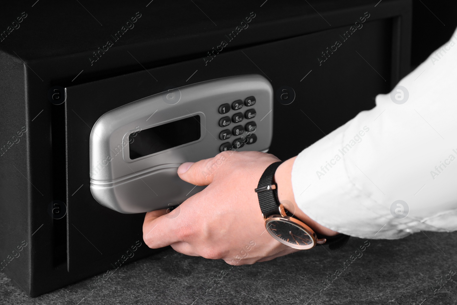 Photo of Man opening black steel safe with electronic lock, closeup