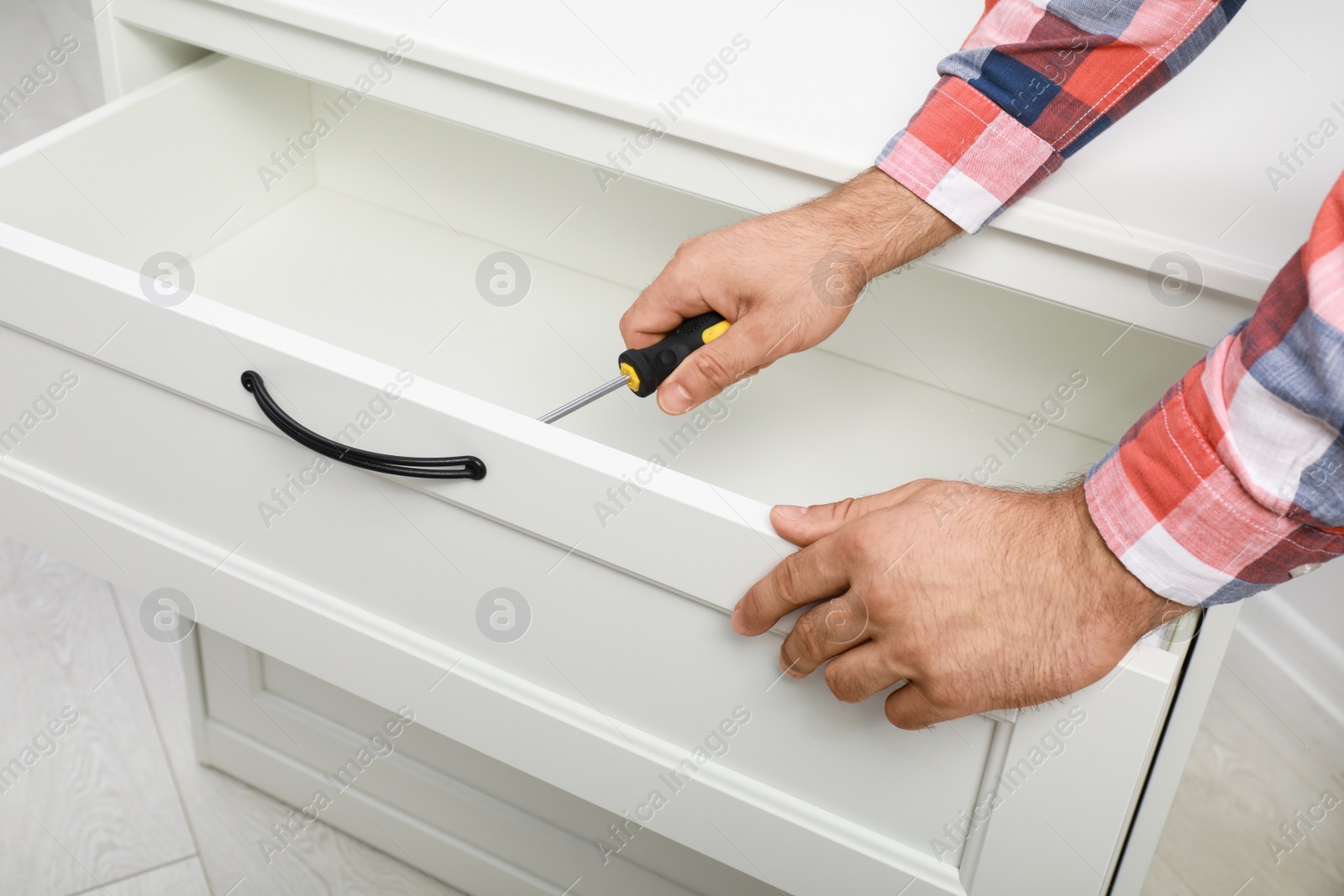 Photo of Man repairing chest of drawers indoors, closeup