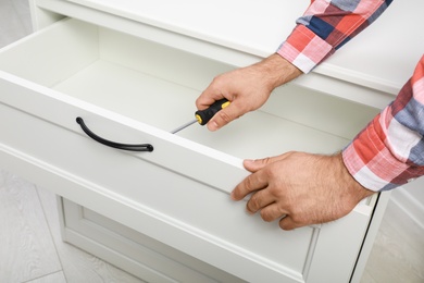 Man repairing chest of drawers indoors, closeup