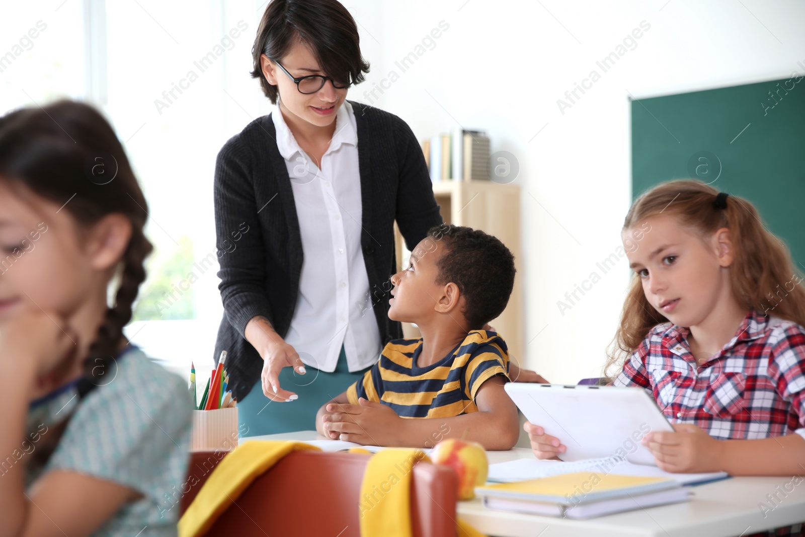 Photo of Female teacher helping child with assignment at school