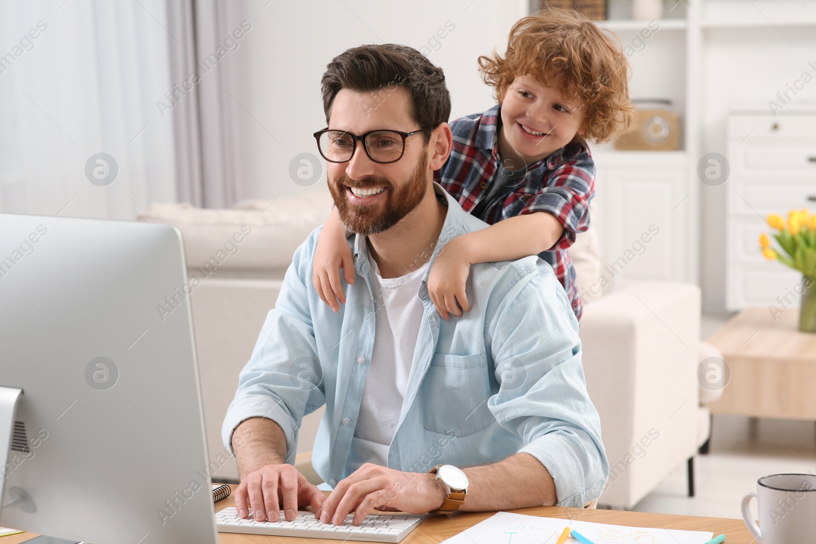 Photo of Man working remotely at home. Father with his child at desk