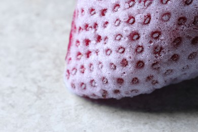 Photo of One frozen ripe strawberry on light table, closeup