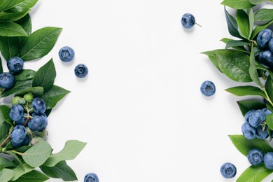 Tasty fresh blueberries with green leaves on white background, flat lay. Space for text