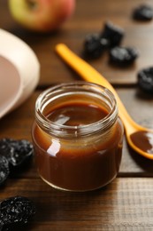 Tasty baby food in jar, spoon and dried prunes on wooden table