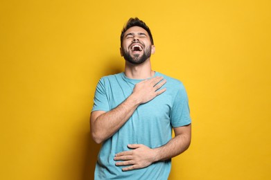 Photo of Young man laughing on yellow background. Funny joke