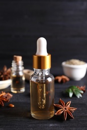 Photo of Anise essential oil and spice on dark wooden table