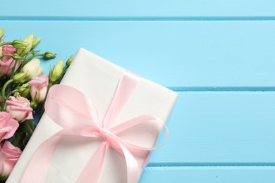 Photo of Happy Mother's Day. Beautiful flowers and gift box on light blue wooden table, flat lay. Space for text